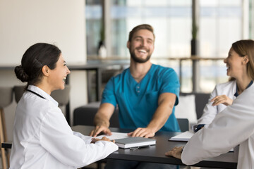 Cheerful young Indian doctor woman laughing at professional meeting with practitioner colleagues,...