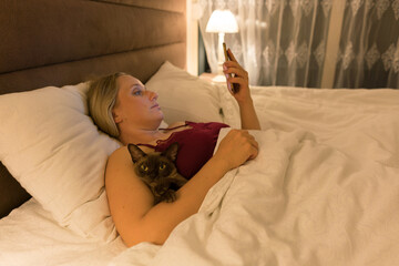 woman in bed before going to sleep with phone in hand