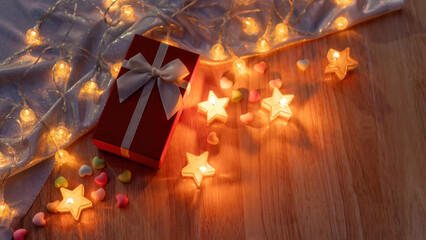 Red gift box and candlelight on a wooden table.