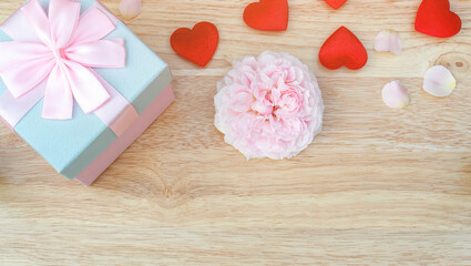 Pink rose and gift box on a wooden table.