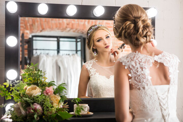 Young pretty smiling bride near mirror