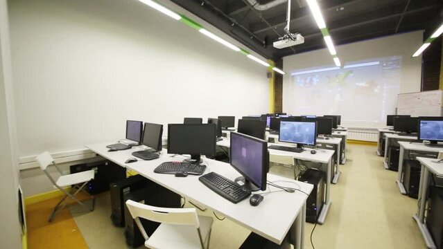 Empty classroom with computers. Text on paper: cost of printing