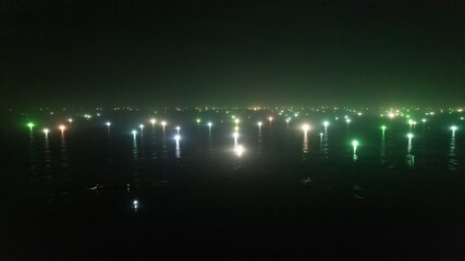 Night view of illuminated docks on a calm lake with reflections of lights on the water's surface,...