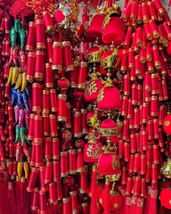 Obraz premium An array of traditional red and gold Chinese decorative items, possibly for the Lunar New Year, featuring lanterns, knots, and firecrackers hanging densely together
