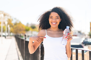 Young African American woman with a bottle of water at outdoors with surprise facial expression