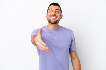 Young handsome caucasian man isolated on white background shaking hands for closing a good deal