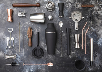 Various cocktail bar utensils set. Strainer,shaker,jigger,straw,juicer,muddler,wine opener on black stone background.