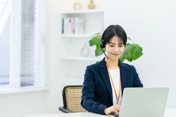 オフィスで仕事をするコールセンターの若い日本人女性