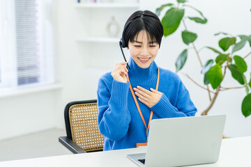 オフィスで仕事をするコールセンターの若い日本人女性