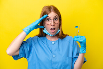 Young redhead Dentist woman isolated on yellow background with surprise expression