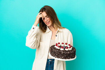 Caucasian woman holding birthday cake isolated on blue background laughing