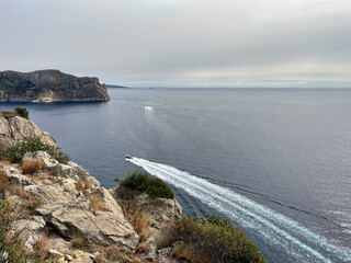 View of the coast and the sea from the Mirador de Sa Mola viewpoint near the town of Port d'Andratx on the Spanish holiday island of Mallorca, and a motorboat passes by