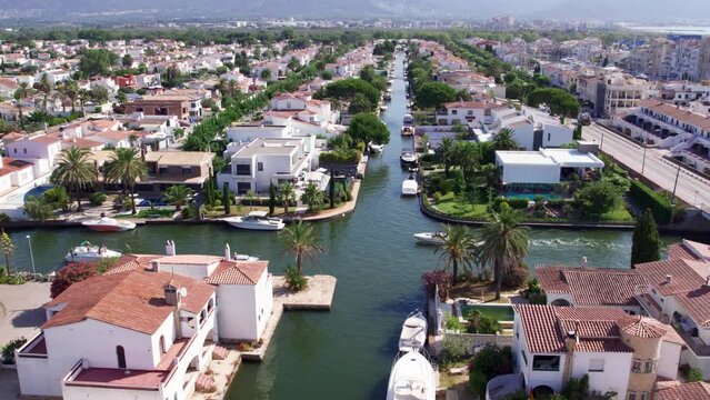 Camera flies over largest residential marina in Europe. Dream spot for a summer vacation or buying property. Tourist boat sail navigate waterways, weaving through canals of Empuriabrava.