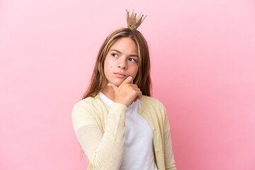 Little princess with crown isolated on pink background having doubts