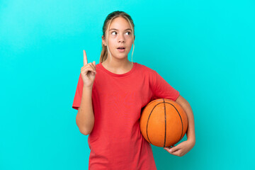 Little caucasian girl playing basketball isolated on blue background thinking an idea pointing the finger up