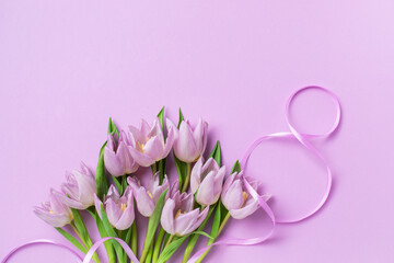 International Women's Day greeting card. Number 8 from satin ribbon and bouquet of beautiful tulip flowers on pastel lilac background top view.