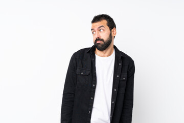 Fototapeta premium Young man with beard over isolated white background making doubts gesture looking side