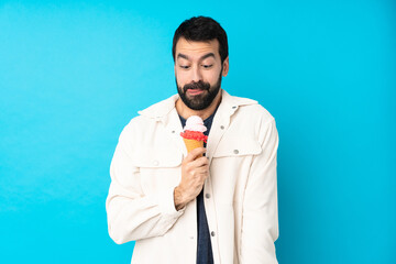 Young man with a cornet ice cream over isolated blue background