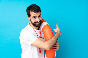 Naklejka premium Lifeguard man over isolated blue background pointing back