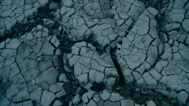 Close up shot of dry cracked terrain, mud from riverbed or earth ground on agricultural field. Signs of drought and climate change effects on nature. Gloom and dark image of post apocalypse