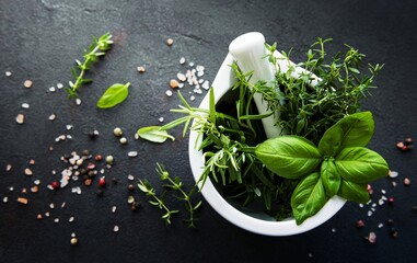 Bunch of aromatic herbs in mortar on a black concrete background