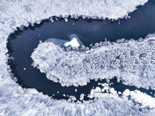 River flowing in snow-covered forest in winter, Poland.