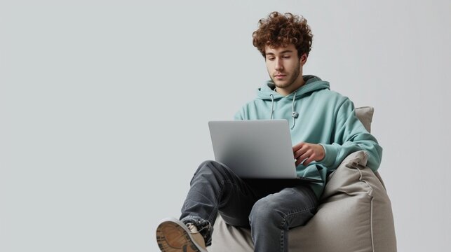 Full Body Young Programmer Happy Caucasian IT Man Wear Mint Hoody Sit In Bag Chair Hold Use Work Point Finger On Laptop Pc Computer Isolated On Plain Solid White Background People Lifestyle Concept.