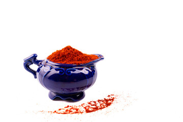 Grated paprika in a blue ceramic dishware on a white background. - 714668708