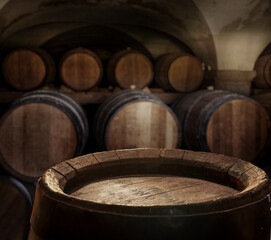 Empty top of  wooden barrel and  wood barrels in cellar at the background. Sun ray falling down to it surface.