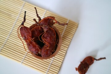 Asam Jawa or Tamarindus indica. Tamarind beans in a bowl on a white background, healthy fruit. Selective focus.