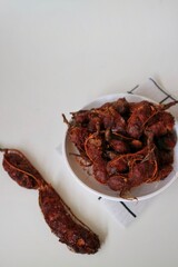 Asam Jawa or Tamarindus indica. Tamarind beans in a bowl on a white background, healthy fruit. Selective focus.