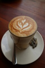 Coffee on wooden tabble. A cup of cappuccino with latte art with love art on the top surface. Fresh morning coffee with delicious milk foam on the cafe. clomplemented with Kwaci or Sunflower seeds.