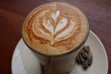 Coffee on wooden tabble. A cup of cappuccino with latte art with love art on the top surface. Fresh morning coffee with delicious milk foam on the cafe. clomplemented with Kwaci or Sunflower seeds.