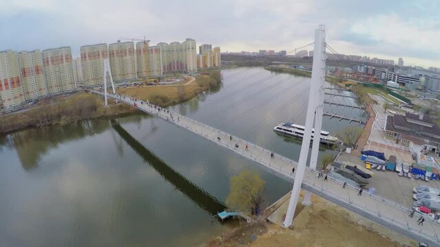 Cable bridge with many pedestrians walk over river 