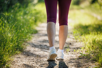 Woman wearing leggings and sport shoe. Athlete person is walking on footpath outdoors. Healthy lifestyle fitness activity
