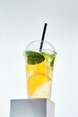 Lemonade with lemon, orange, lime and mint in transparent plastic glass on white background