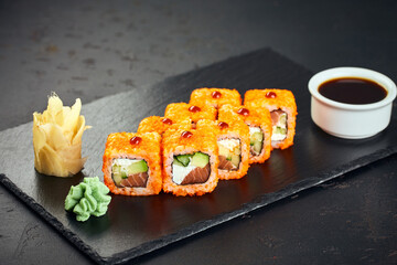 Philadelphia sushi roll with tuna, avocado, cream cheese, cucumber and tobiko caviar on dark background. Sushi menu. Japanese food.