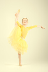 Naklejka premium Portrait of a young gymnast. A cute girl is a professional rhythmic gymnast. Yellow background