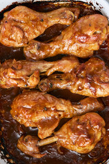 Chicken drumsticks baked in sauce in a baking dish close-up