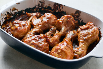 Chicken drumsticks baked in sauce in a baking dish close-up