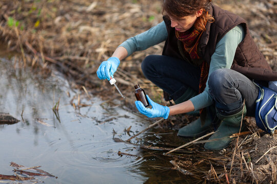 Adult Caucasian Woman Biologist Working on Field Checking Mechanical Pollution of Water Pond in City Park
