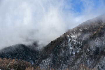 雨上がりの雲に覆われる雪山と青空
