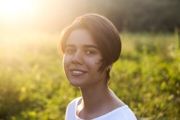 Portrait of cute brunette teen girl walking at meadow field