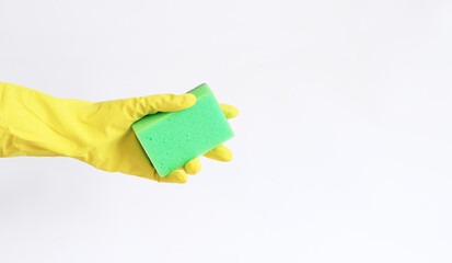A woman's hand in a yellow latex glove holds a dishwashing sponge. Cleaning the premises. Professional cleaning. Household gloves, yellow. Cleaning woman