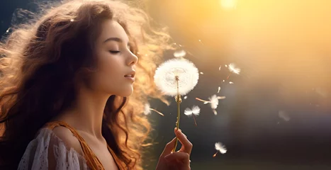 Fotobehang Young woman blowing on fluffy dandelion flower on blurred natural background © Bonsales