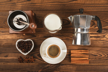 Ingredients for making coffee. Moka pot, Turkish coffee pots (cezve), coffee grinder with coffee beans, milk, sugar and spices on a brown background. Drink preparation concept. Flat Lay.Copy space.