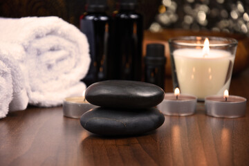 Fototapeta na wymiar Spa massage hot stones, white towels and candles on wooden background still life stock photo images. Spa and wellness setting with towels, candles and pebbles. Beauty spa treatment composition images