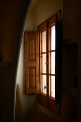 Light enters a wooden window and falls on the walls of a darkened attic room