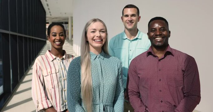Portrait of professional staff members, four young multiethnic employees standing in modern office hallway smile posing for camera. Promotion, hiring, human resources, achievements and career growth