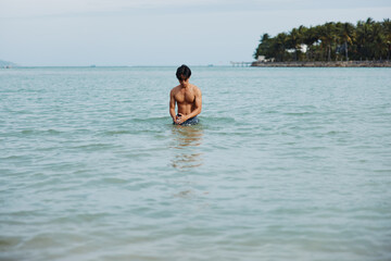 Active Asian Man Enjoying Tropical Vacation by Swimming in the Beautiful Blue Ocean